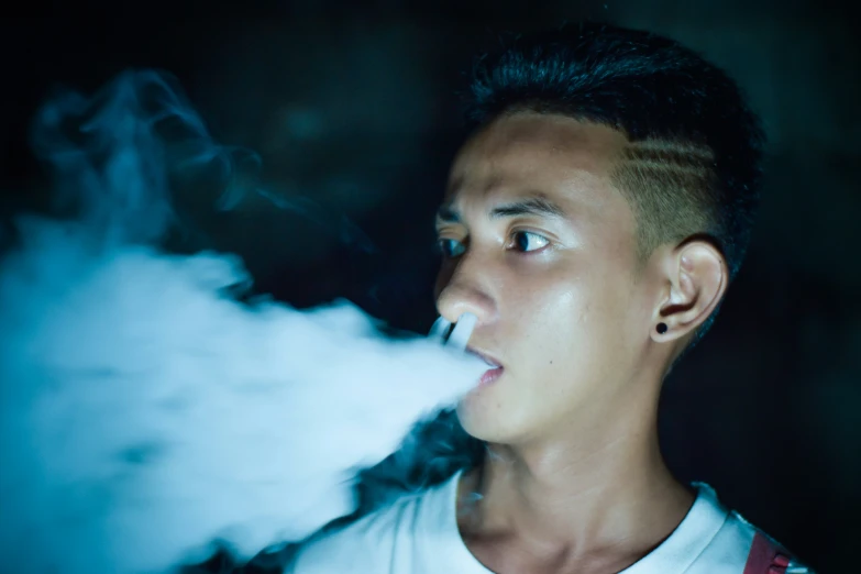 a boy in white shirt smoking a cigarette