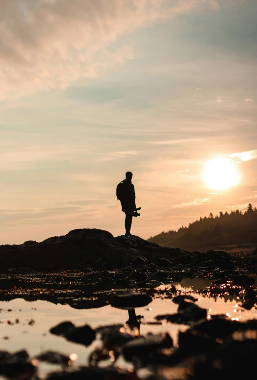 a lone skier standing on top of a mountain at sunset