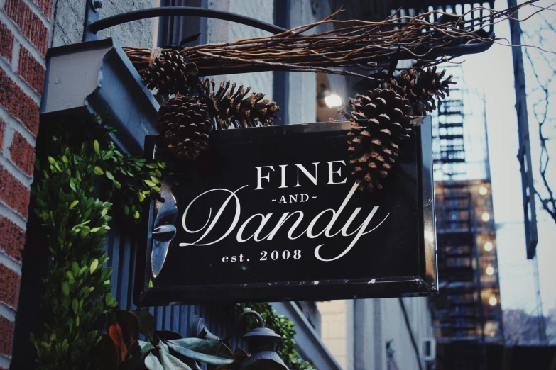 a black sign that says fine and dandy in front of a building