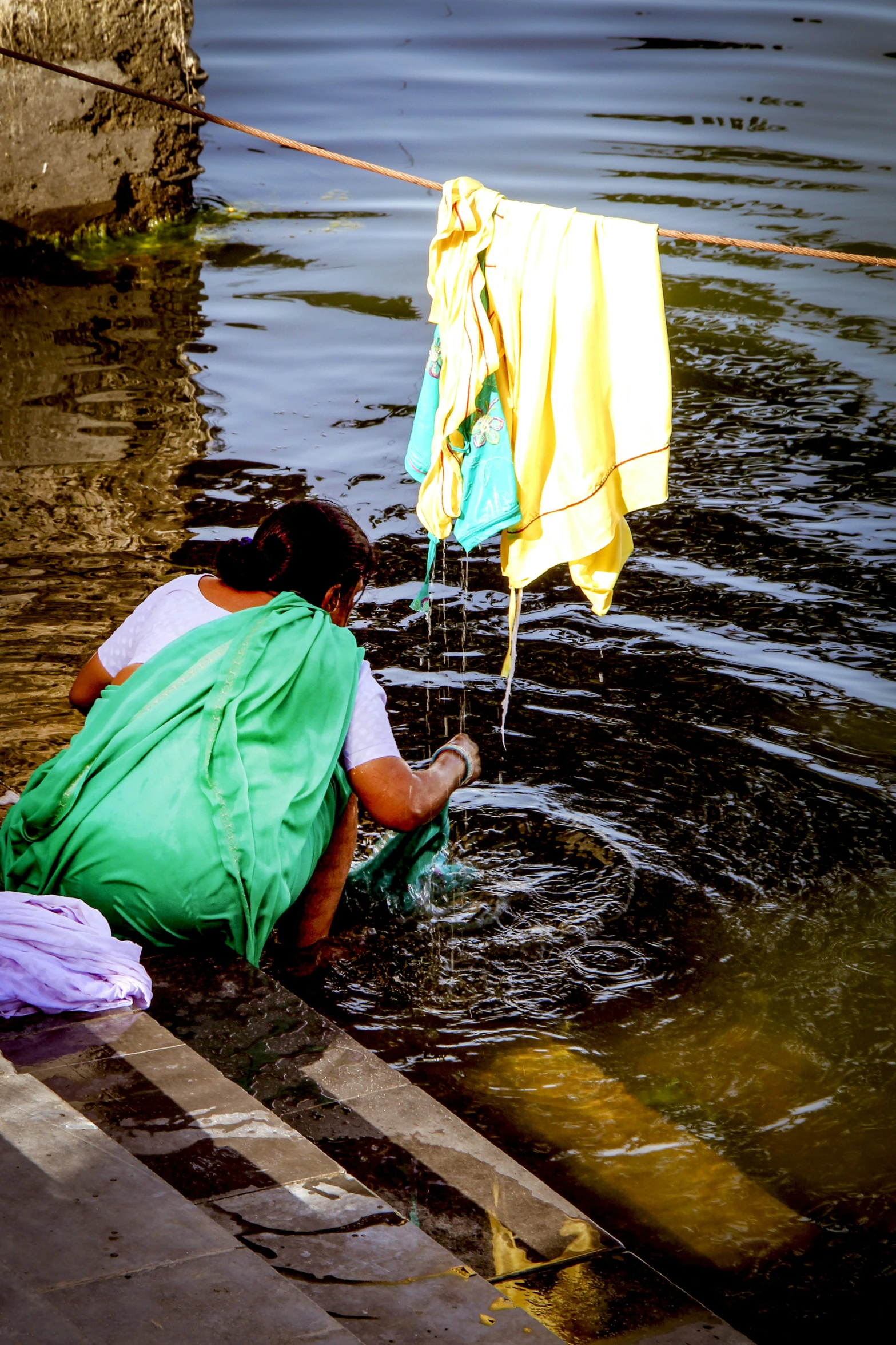 two people washing themselves in water with an orange towel