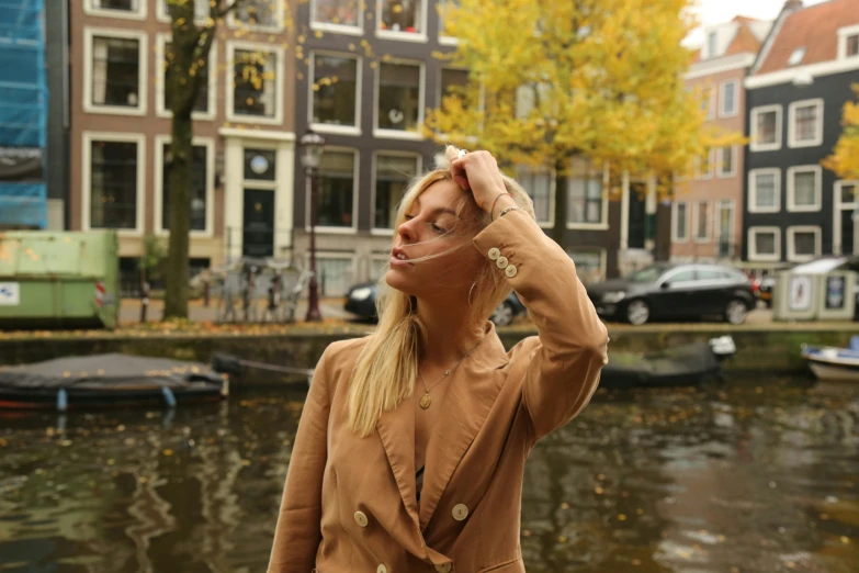 a woman poses in front of a canal and several buildings