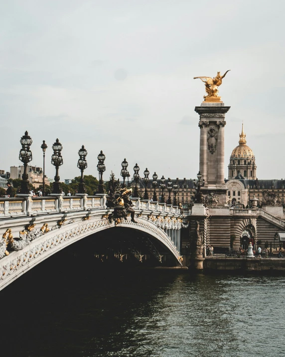 a bridge and water with statues near a city