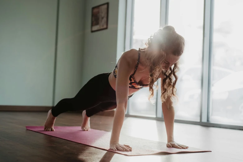a woman does h - ups while on her own yoga mat