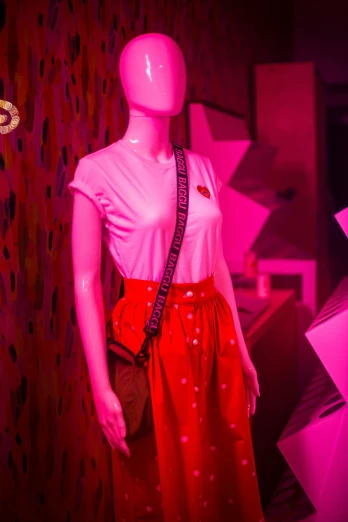 a pink and red dress displayed next to a mannequin