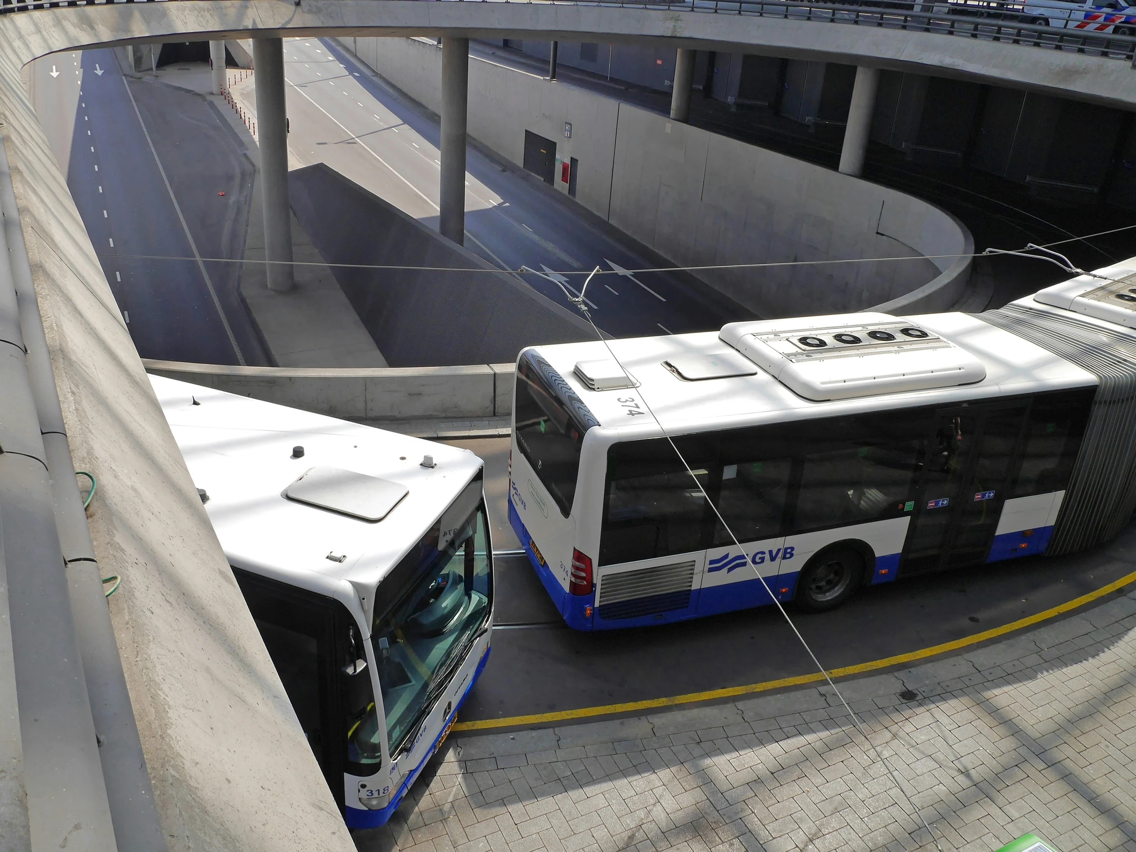 two buses are driving on a city street