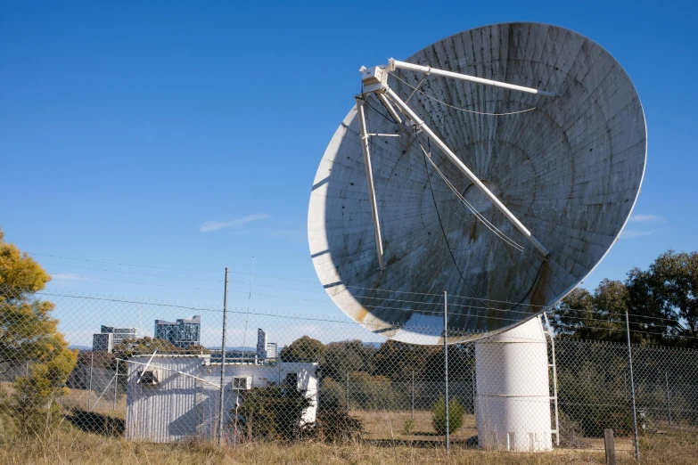 a satellite dish sitting in the middle of a field with lots of grass