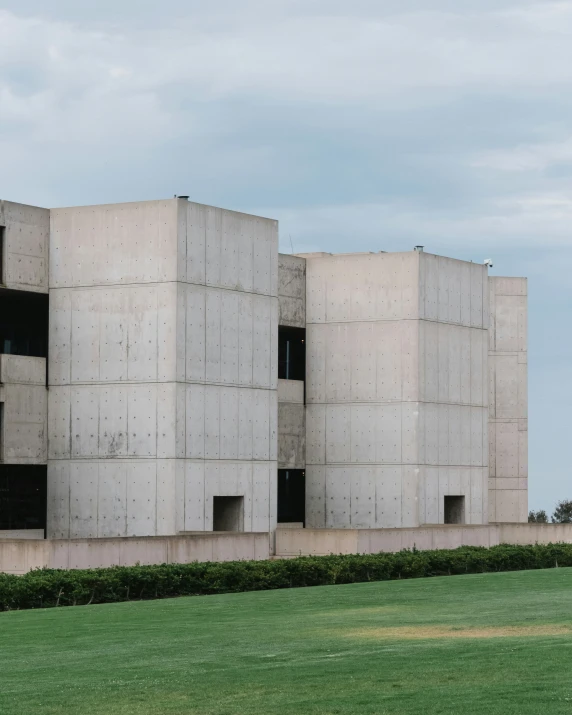 a modern building with tall concrete blocks on the grass
