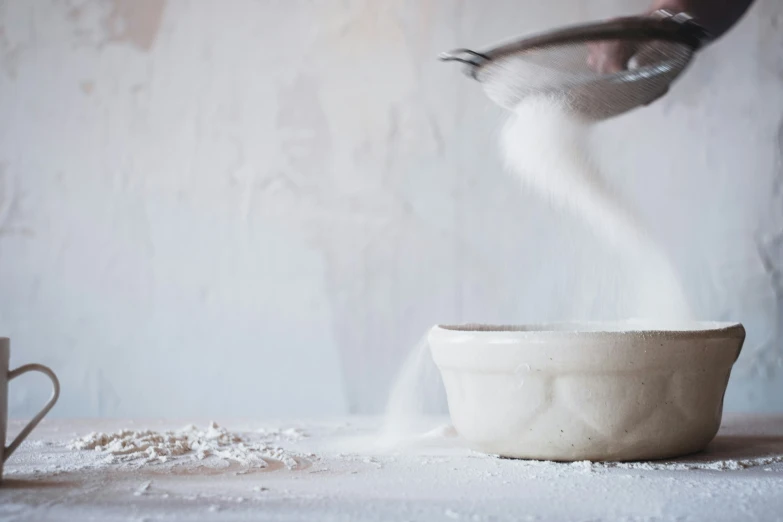 a cup of white sugar sitting on top of a table