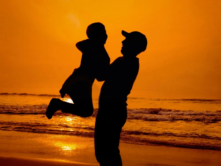 a silhouette of two people facing each other on the beach