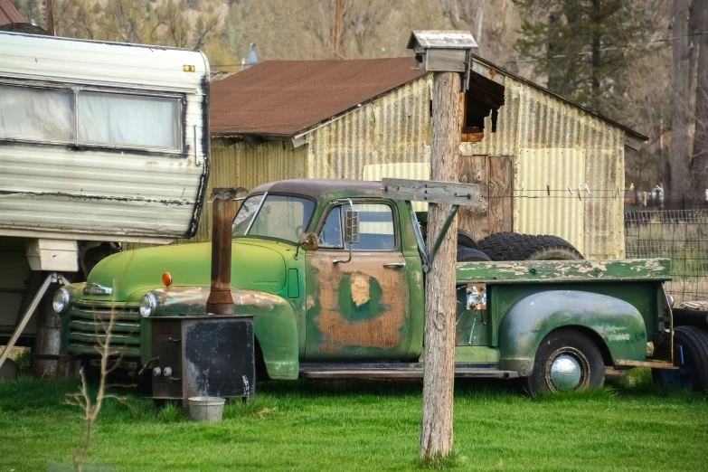 old truck and trailer parked in the grass