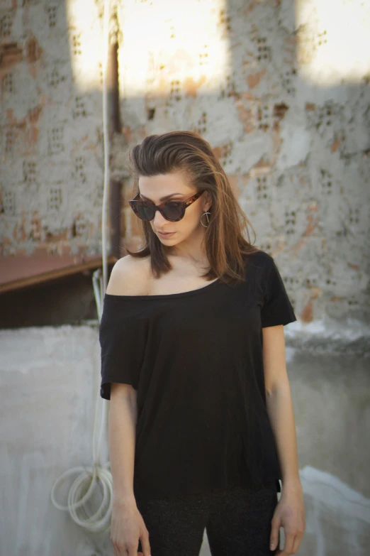 a woman wearing sunglasses stands outside near some graffiti