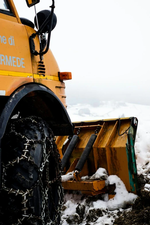 a big yellow truck parked in the snow with chains and snow wheels