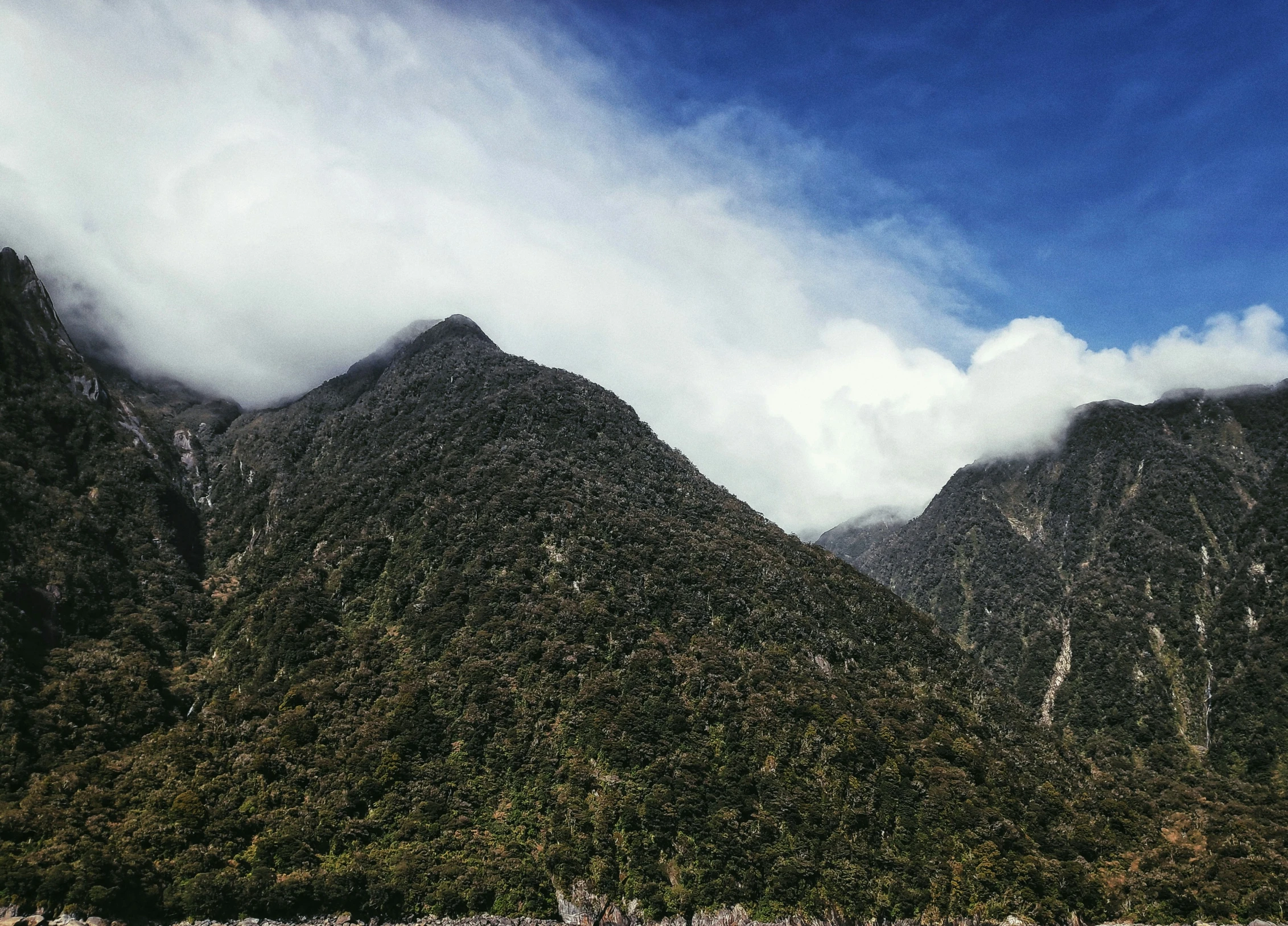 clouds are rolling in on some mountains as the sun shines brightly