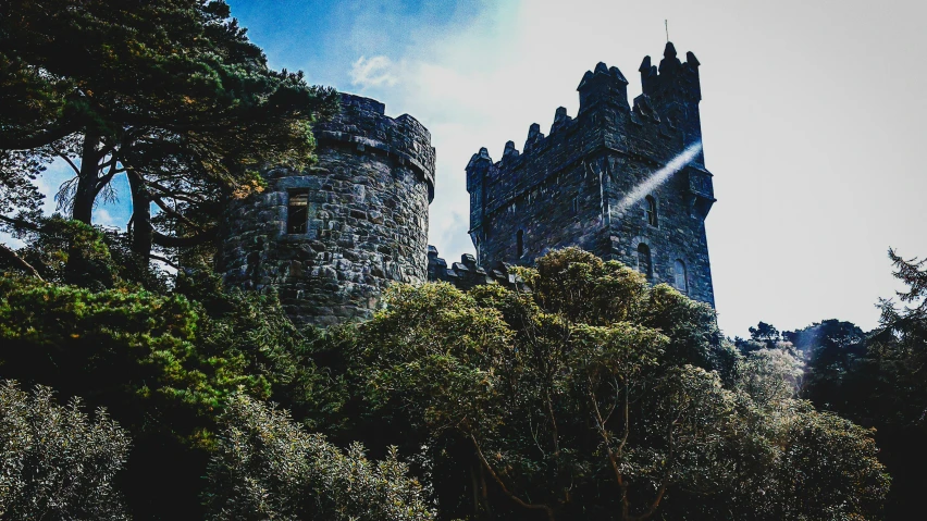 an old castle is surrounded by trees in the sunlight