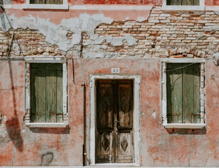 an old brick building with two windows and green shutters