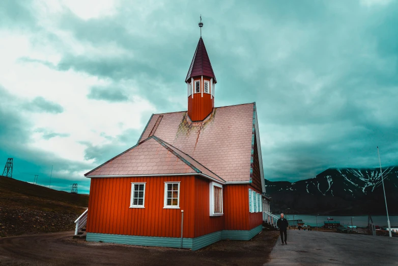 a very red church with a steeple and clock tower on top