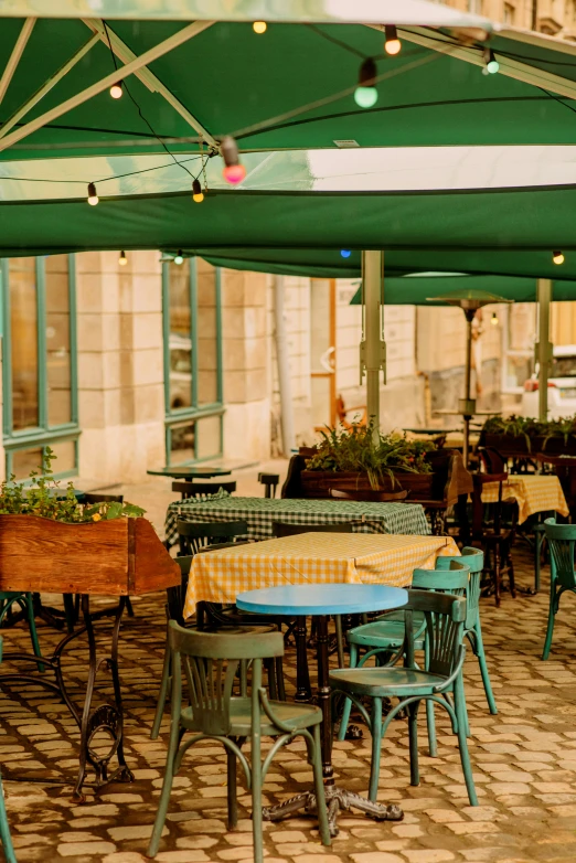 green chairs and tables sit under an umbrella