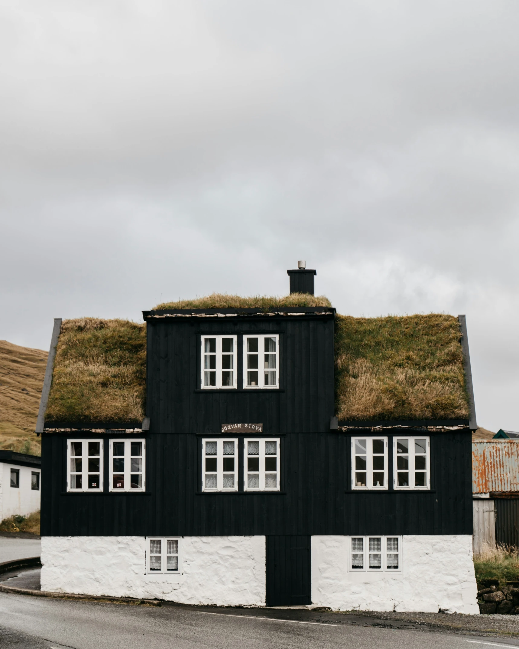 an old black and white house with a green roof