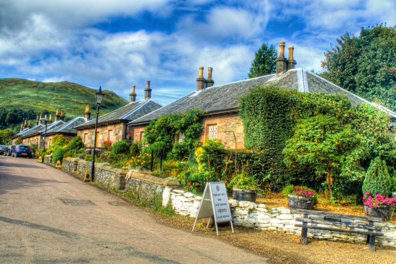 a rural home with lots of trees and flowers in front of it