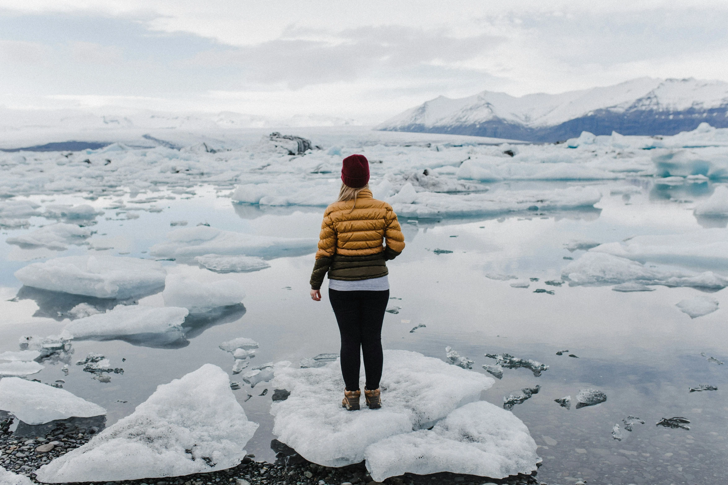 a person stands on an icy surface overlooking glacier