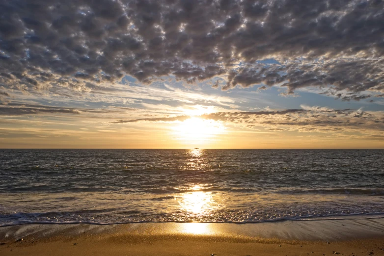 a view of a beach at sunset with waves breaking on it