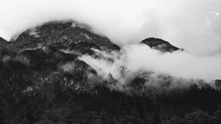 trees, clouds and mountains near each other in black and white