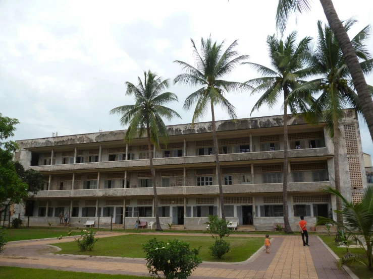 an old building with people standing outside on the lawn