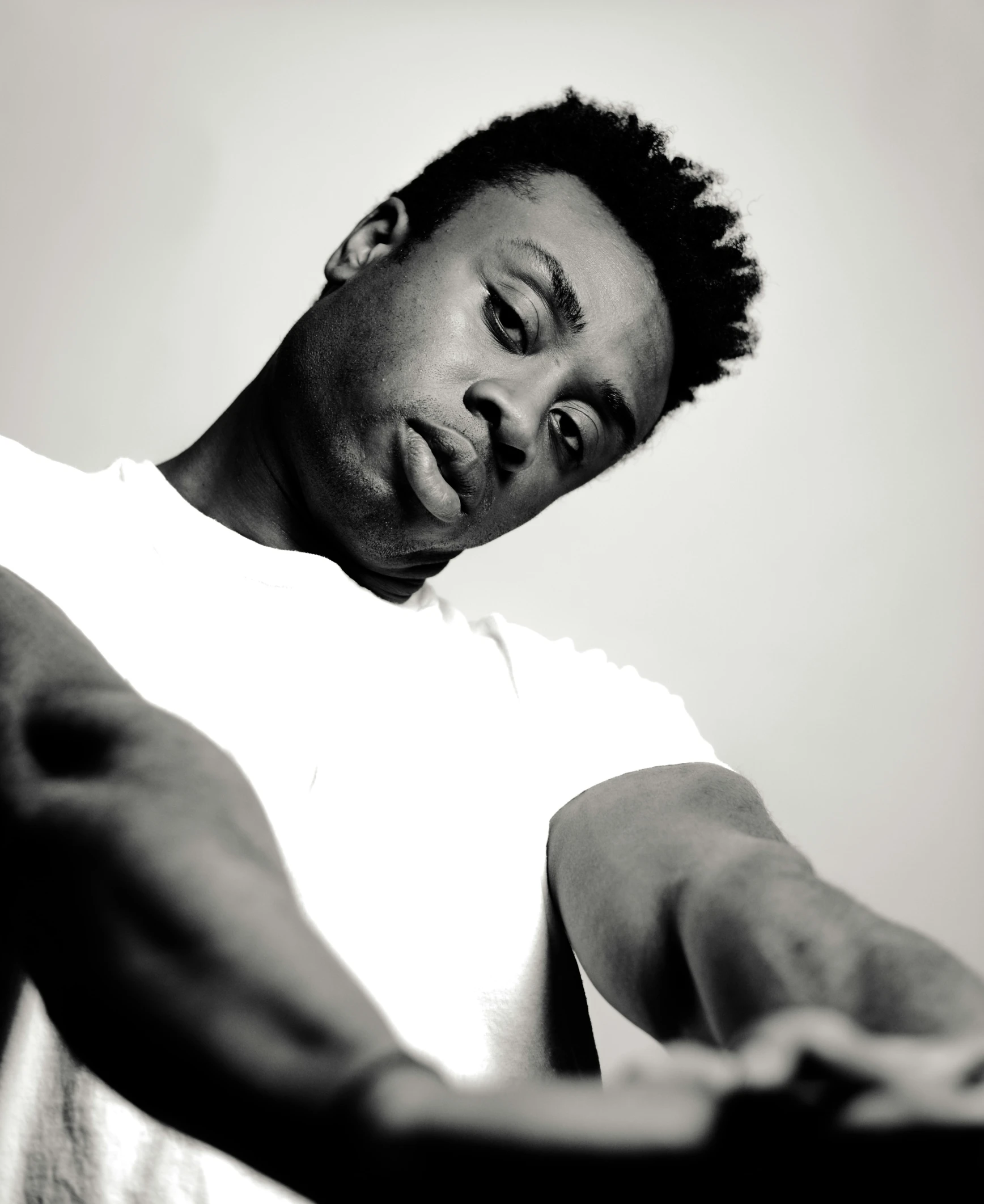 a young man with dreadlocks and white t - shirt stares in anger