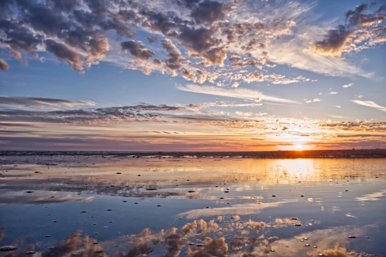 the sun rises over an empty ocean with some clouds