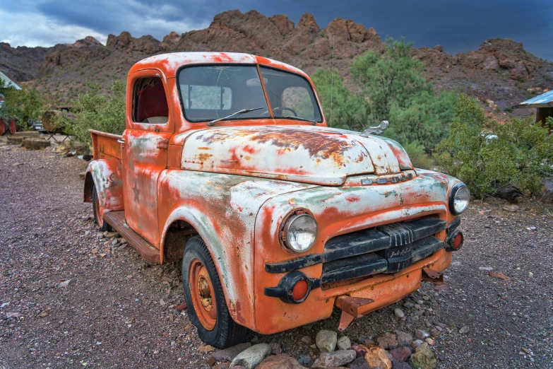 a rusted out truck is parked in the dirt