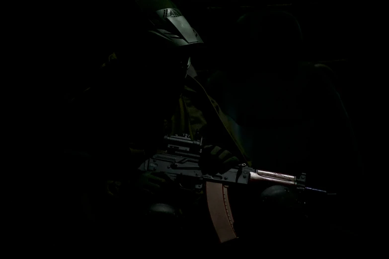 a person is holding up an automatic rifle at night