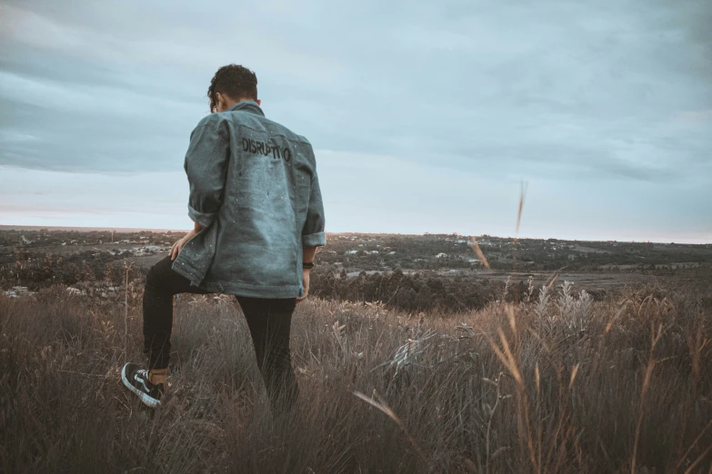 man standing in the middle of a field with his back to the camera