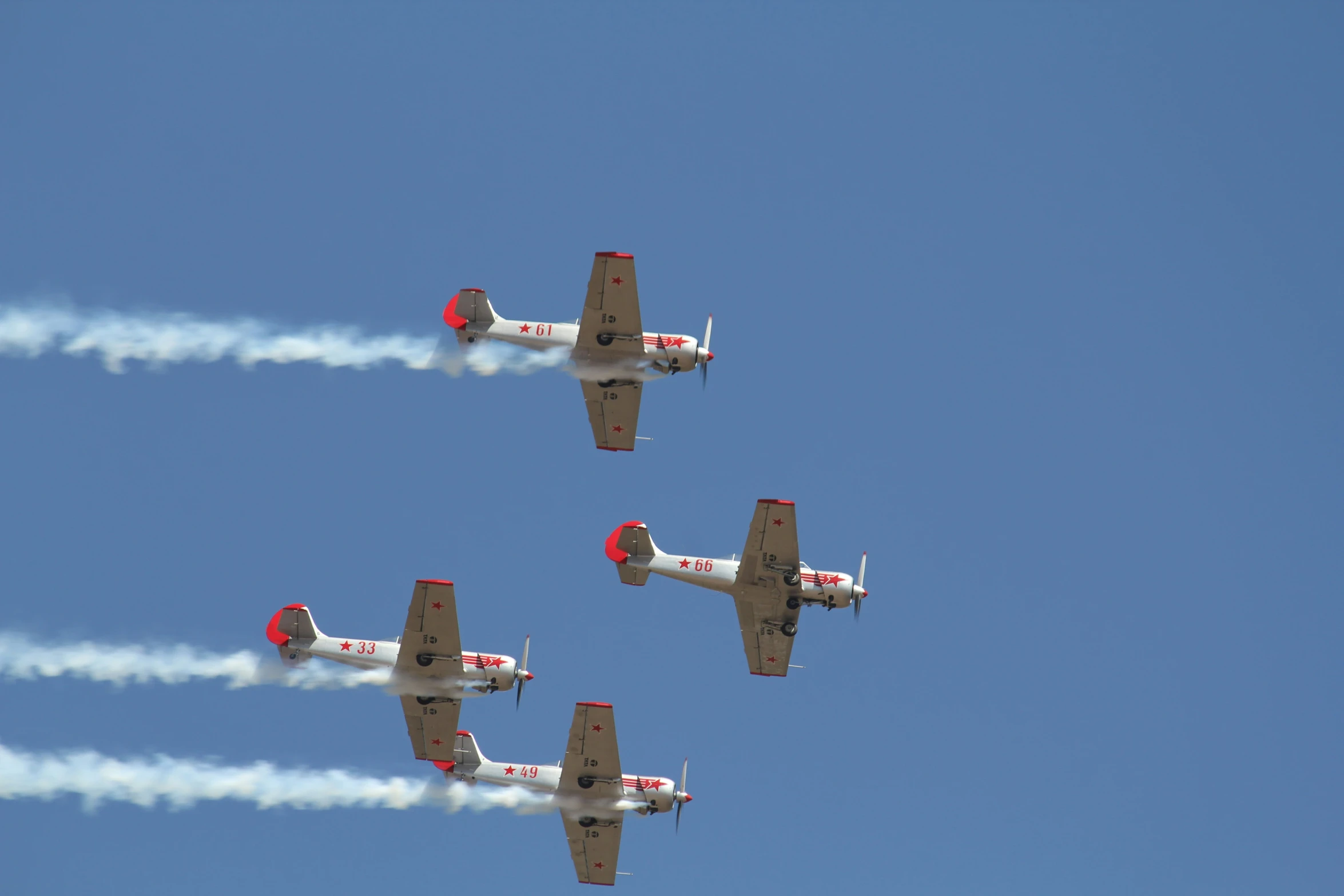 several airplanes flying in formation with smoke coming out of the engine