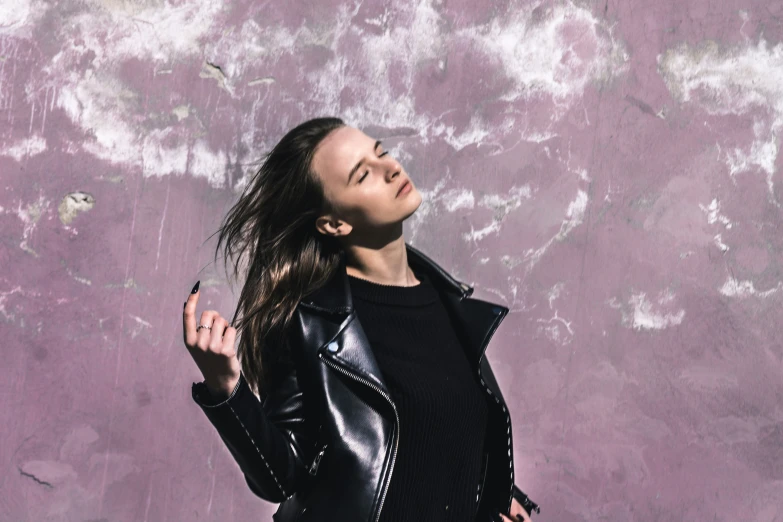 a woman wearing black jacket and pants holding her hair up