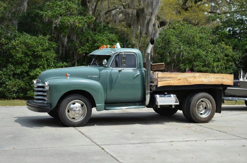 a truck parked on a concrete area with some trees in the background