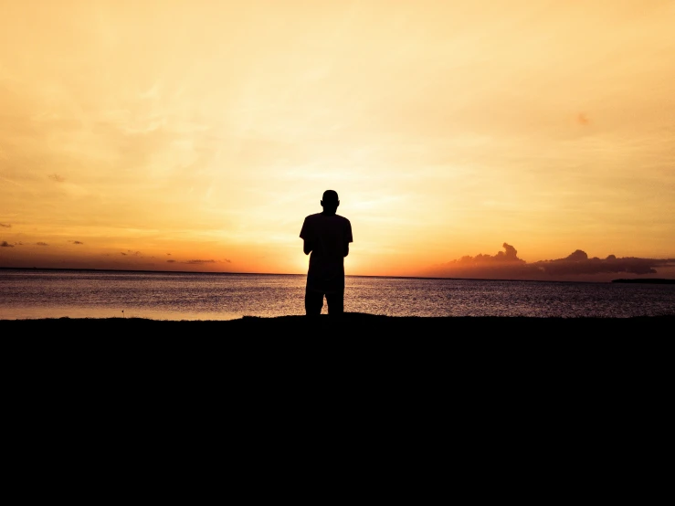 a man standing in the ocean at sunset