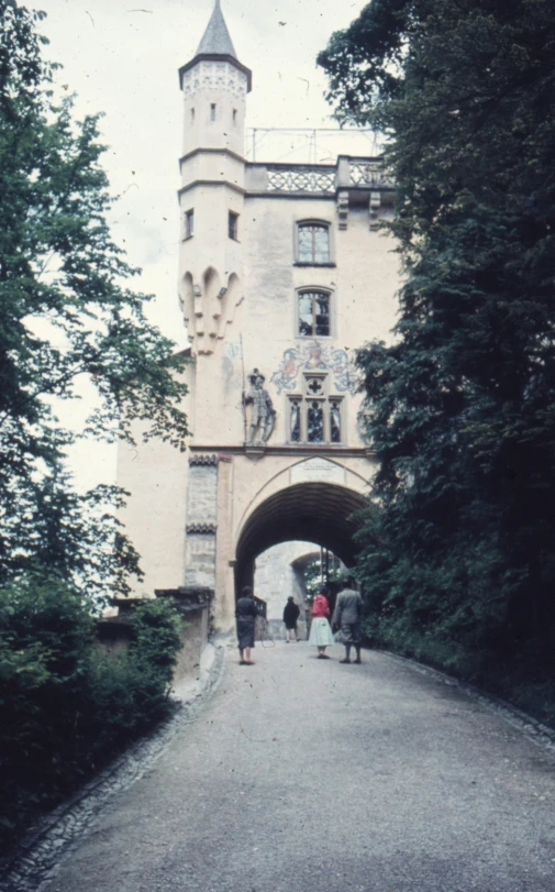 two people with backpacks and one person walking under an old bridge