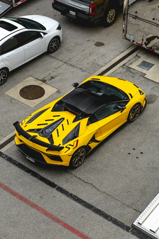 yellow and black sports car parked in the middle of a parking lot