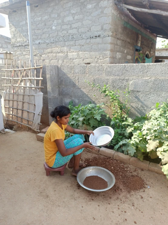 a person is crouched down and putting soing in a bowl