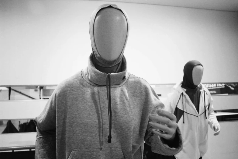 a person in a black hoodie is holding up a white mannequin head