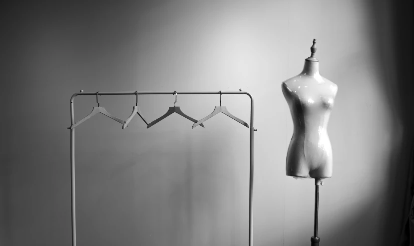 an empty dummy next to a coat rack and clothes hanger