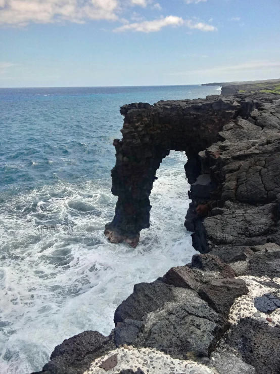 large rock formation with the sea coming towards it