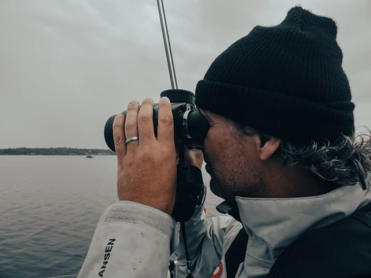 a man looks through binoculars as he watches boats sail through the water