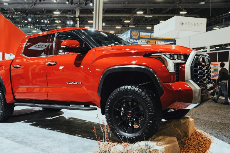 a very bright orange lifted truck parked on display