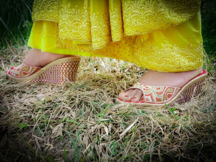 a woman in yellow and pink sandal wearing a red and white slip on her feet