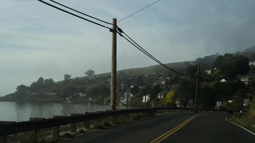 a bus rides on an empty road with some power lines in the distance