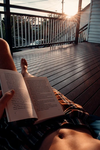 a person laying down on a deck reading a book