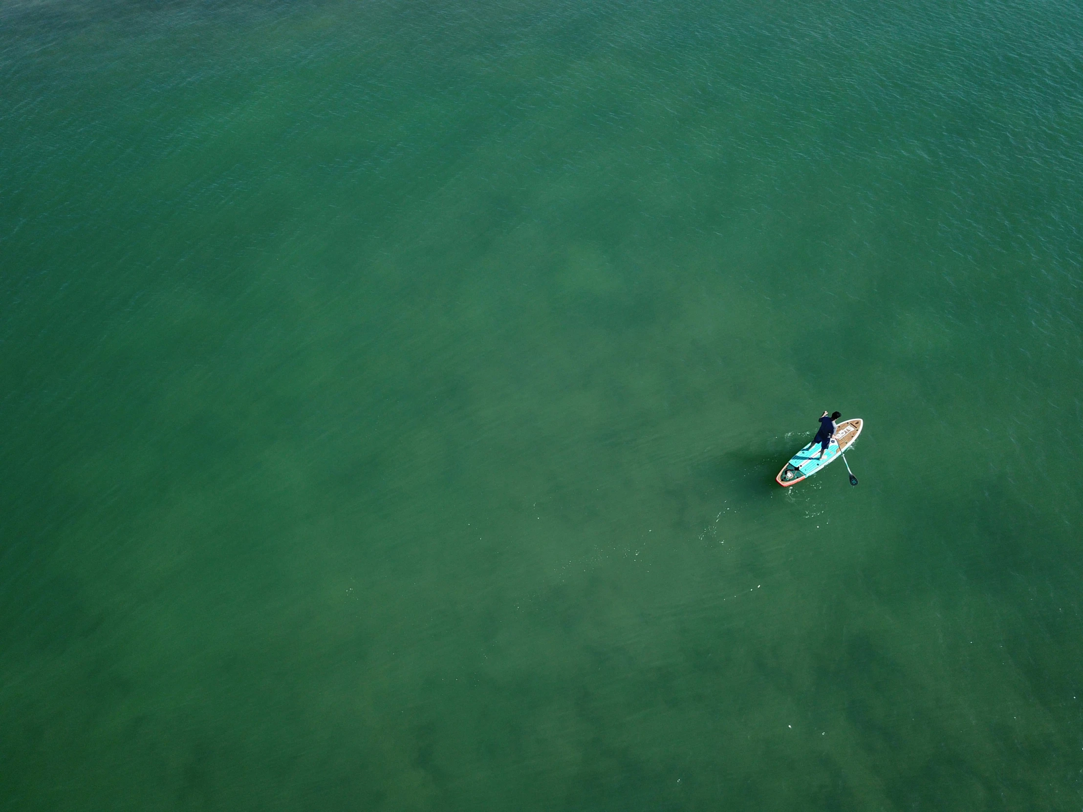 a lone person in a blue boat in a body of water