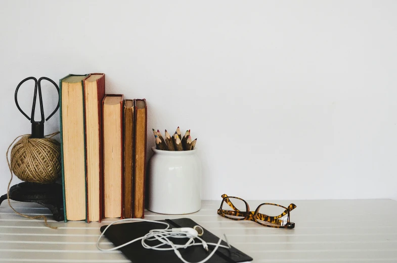 a white mug and some books and glasses on a table