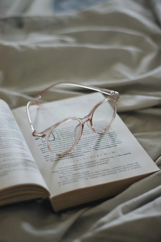 a book with glasses sitting on a bed